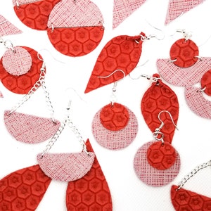 Puede incluir: Un conjunto de pendientes de cuero rojo y rosa con formas geométricas y patrones de panal. Los pendientes están hechos con ganchos de plata y algunos tienen cadenas.