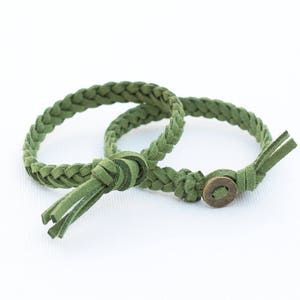May include: Two green braided leather bracelets with a metal button closure.