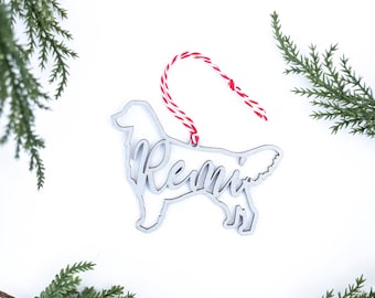 May include: A silver metal Christmas ornament shaped like a golden retriever dog with the name "Remi" cut out inside the silhouette.
