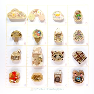 May include: A set of 16 resin charms featuring various cute and whimsical designs, including a cloud, rainbow, mushroom, ice cream cone, milk carton, cat, chocolate bar, gift box, and more. Each charm is filled with colourful glitter and small objects, creating a unique and eye-catching look.