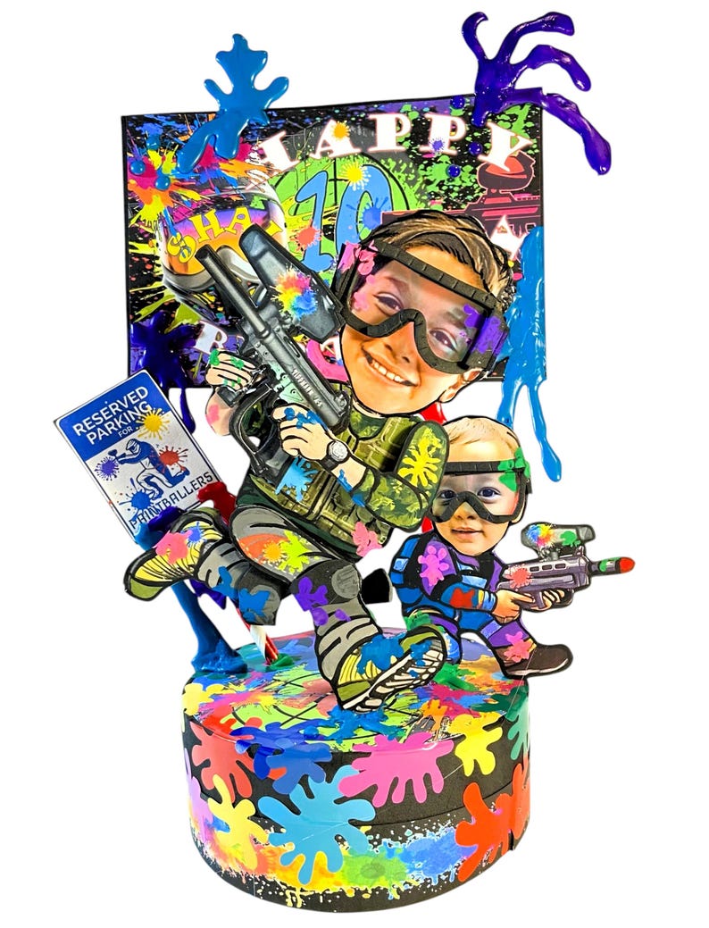 May include: A vibrant paintball-themed cake featuring two cartoon figures, one with a paintball gun. The cake is adorned with paint splatters and the words "Happy 10th Birthday". A sign reads "Reserved Parking for Paintballers".
