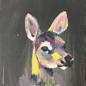 Könnte beinhalten: Ein farbenfrohes Gemälde eines Hirschkopfes vor einem dunklen Hintergrund. Das Hirschfell ist in Gelb-, Rosa- und Lilatönen gemalt, mit schwarzen Akzenten um die Augen und die Nase.