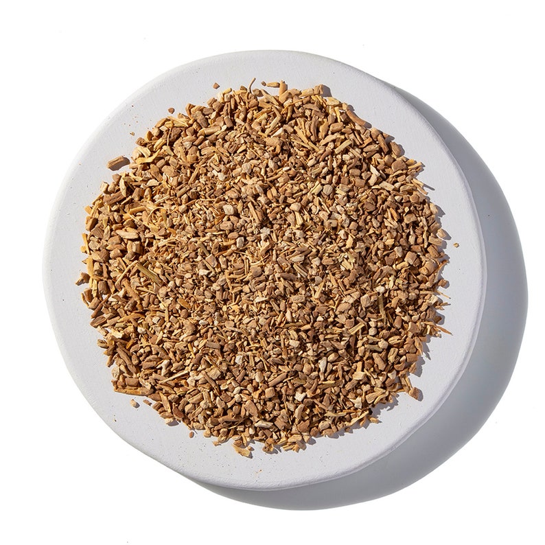 May include: A white ceramic plate filled with dried, light brown, and tan coloured root pieces.