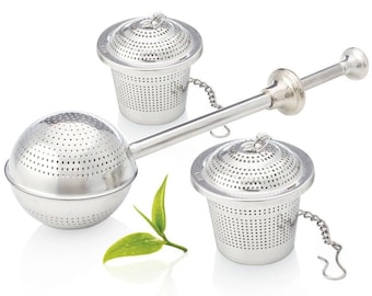 Op de afbeelding: Een roestvrijstalen thee-infuser set met een bol en twee kopvormige zeven. De bolvormige infuser heeft een lange handgreep met een knijpmechanisme. Elke zeef heeft een ketting en een deksel. Een takje groene theebladeren ligt naast de infusers.
