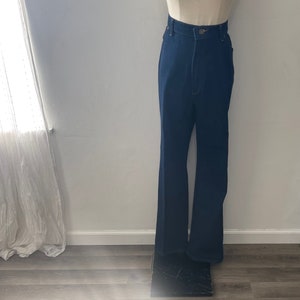 May include: A pair of dark blue denim bell bottom pants. The pants have a high waist and a wide leg.