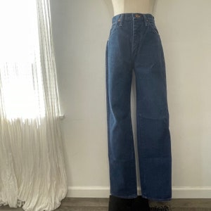 Pu&ograve; includere: Un paio di jeans blu a gamba dritta e vita alta.