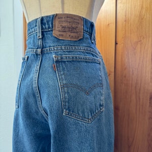 Könnte beinhalten: Eine blaue Jeans aus Denim mit einem braunen Leder-Patch, auf dem "Levi Strauss & Co.  Original  Riveted  Quality  Clothing  550  W 32 L 32" steht.