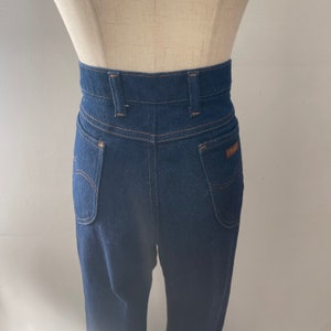 May include: Dark blue high-waisted jeans with a brown leather patch on the back pocket.