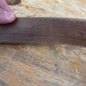 May include: Close-up of a brown leather belt with the number "28" embossed on it.