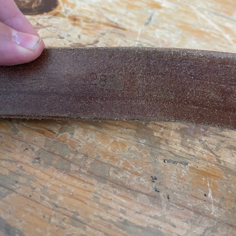 May include: Close-up of a brown leather belt with the number "28" embossed on it.