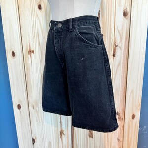 May include: Black denim shorts with a classic five-pocket design. The shorts have a straight leg and a relaxed fit.
