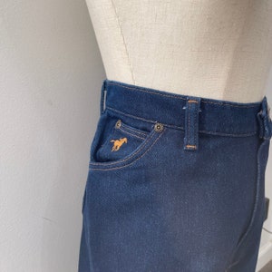 May include: Dark blue denim skirt with a small horse logo embroidered on the front pocket.