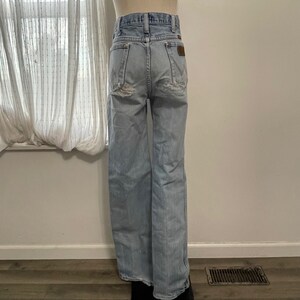 May include: Light blue denim jeans with a wide leg and a high waist. The jeans have a distressed look with rips and tears throughout.