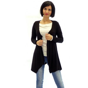 Peut inclure: Un cardigan noir &agrave; manches longues avec un devant drap&eacute; et une fermeture boutonn&eacute;e. Le cardigan est port&eacute; sur une chemise blanche &agrave; rayures et un jean bleu.