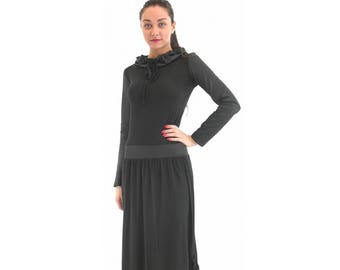 Pode incluir: Um vestido preto de manga comprida com decote de babados e saia franzida.