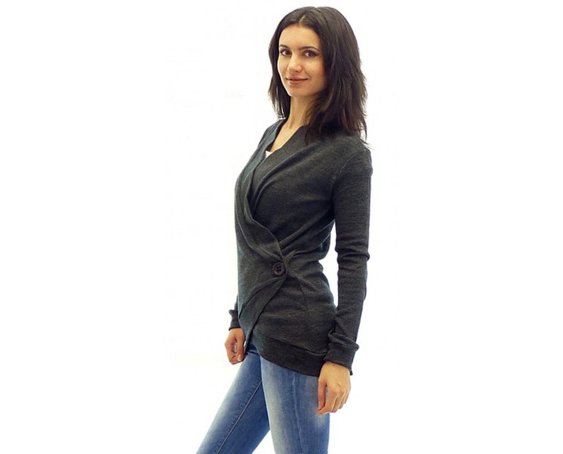 May include: A dark gray wrap cardigan with a single button closure. The cardigan is made of a soft, knitted fabric and has a relaxed fit.