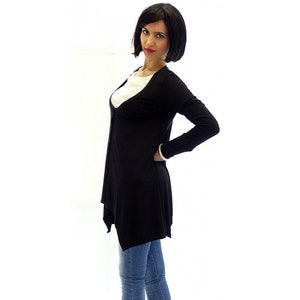 Peut inclure: Un cardigan noir &agrave; manches longues avec un col en V et une ourlet l&eacute;g&egrave;rement asym&eacute;trique. Le cardigan est port&eacute; sur un t-shirt blanc et un jean bleu.