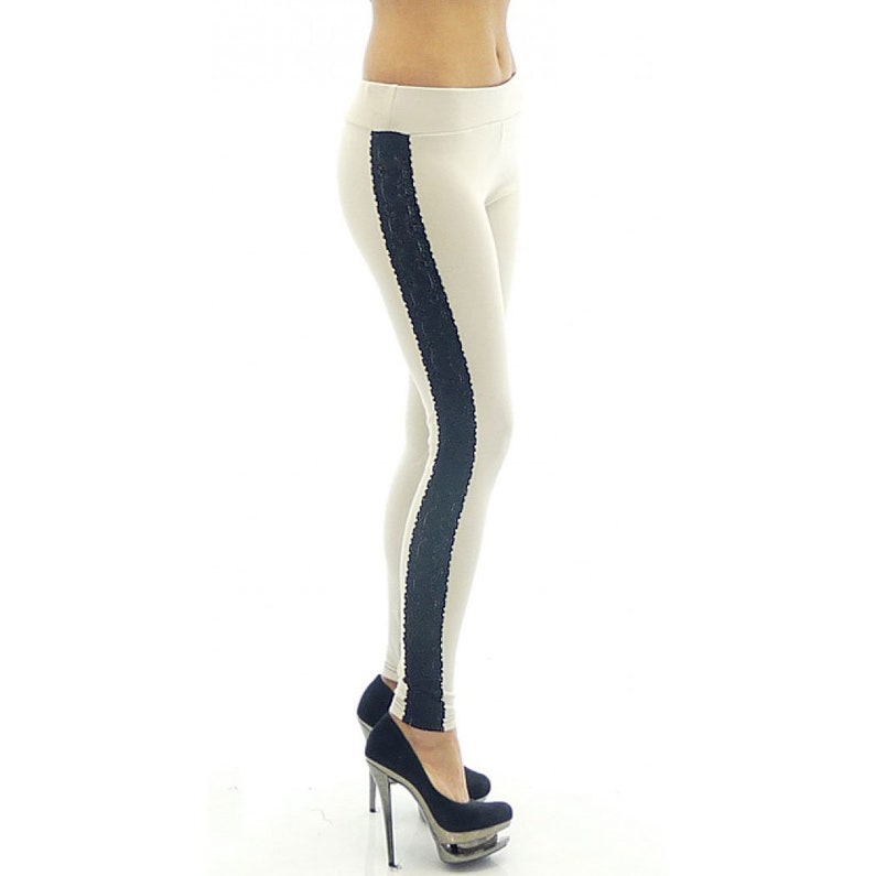 May include: Beige leggings with a black lace stripe down the side. The leggings are worn by a person wearing black high heels.