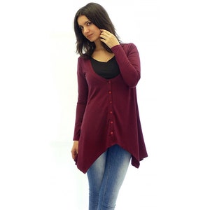 Peut inclure: Un cardigan long &agrave; manches longues de couleur bordeaux avec un devant boutonn&eacute; et une ourlet l&eacute;g&egrave;rement asym&eacute;trique. Le cardigan est fait d'un tissu doux et extensible.
