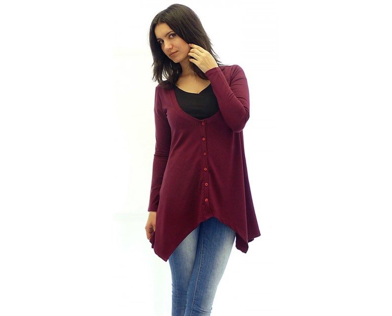 Peut inclure: Un cardigan long &agrave; manches longues de couleur bordeaux avec un devant boutonn&eacute; et une ourlet l&eacute;g&egrave;rement asym&eacute;trique. Le cardigan est fait d'un tissu doux et extensible.
