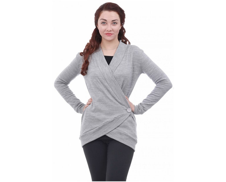 May include: A gray wrap cardigan with a single button closure. The cardigan has a long sleeve and a relaxed fit.