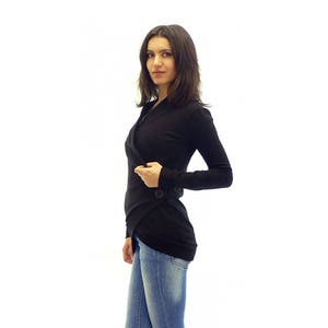 May include: A black long-sleeved wrap top with a single button closure. The top is worn with blue jeans.
