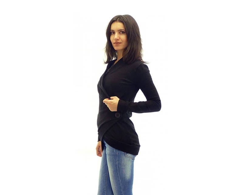 May include: A black long-sleeved wrap top with a single button closure. The top is worn with blue jeans.