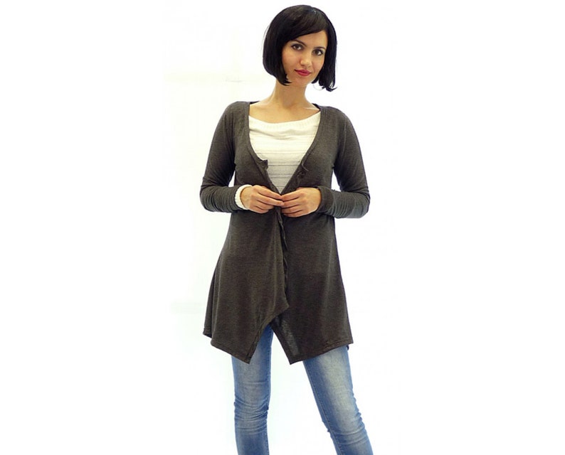 Peut inclure: Un cardigan gris anthracite &agrave; manches longues avec une ourlet asym&eacute;trique drap&eacute;. Le cardigan est ouvert &agrave; l'avant et se ferme par un bouton.
