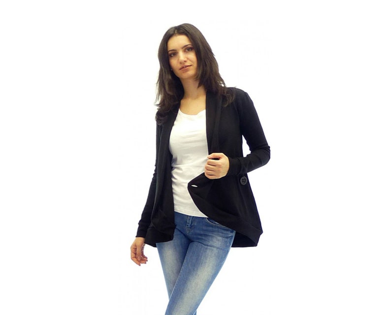 May include: A black cardigan with a long, flowing design and a single button closure. The cardigan is worn over a white t-shirt and blue jeans.