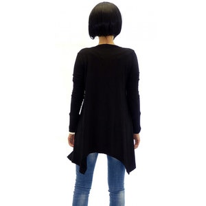 Peut inclure: Chemise noire &agrave; manches longues avec une ourlet asym&eacute;trique. La chemise est faite d'un tissu doux et extensible et a une coupe d&eacute;contract&eacute;e.