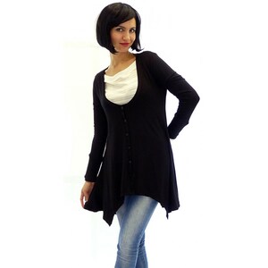 Peut inclure: Un cardigan noir &agrave; manches longues avec un devant boutonn&eacute; et une ourlet l&eacute;g&egrave;rement asym&eacute;trique. Le cardigan est port&eacute; sur une chemise blanche et un jean bleu.