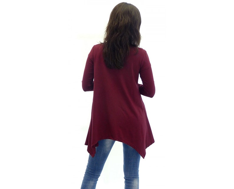 Peut inclure: Un chemisier &agrave; manches longues de couleur bordeaux avec une coupe asym&eacute;trique. Le chemisier est fait d'un tissu doux et extensible et a une coupe d&eacute;contract&eacute;e.
