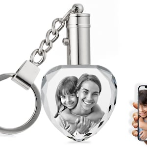 May include: A silver heart-shaped crystal keychain with a photo of two people inside. The keychain has a silver chain and a silver ring.