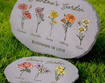 May include: Two gray stone garden markers with floral designs and names. The larger stone reads "Grandma's Garden" and features illustrations of flowers with names like Michael and Olivia. The smaller stone says "Nana's Garden" with names like Hillary and Jessica.