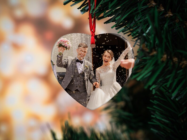 May include: A heart-shaped ornament with a photo of a bride and groom exiting a ceremony. The couple is smiling and holding hands as they walk down the aisle. Confetti is falling around them.