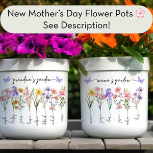 May include: Two white ceramic flower pots with floral designs and the text "grandma's garden" and "mama's garden". The pots are filled with vibrant purple and orange flowers. The top banner reads "New Mother's Day Flower Pots See Description!"