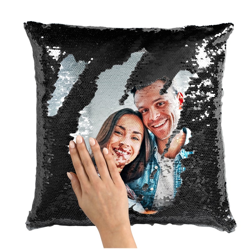 May include: A black sequin pillow with a photo of a couple smiling at the camera. The sequins can be flipped to reveal the photo.