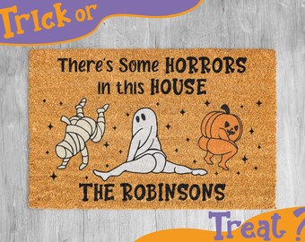 May include: A brown doormat with the text "There's some HORRORS in this HOUSE THE ROBINSONS" and illustrations of a mummy, a ghost, and a pumpkin.