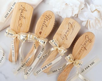 Puede incluir: Cuatro cepillos de pelo de bambú marrón claro con los nombres grabados Amelia, Melissa, Emily y Beatrice. Cada cepillo está atado con una cinta color crema con el texto negro repetido JUST FOR YOU, decorado con pequeños corazones.