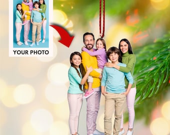 May include: A Christmas bauble featuring a family of six people, including a father, mother, and four children. The bauble is made of a white material and has a red string for hanging. The family are smiling and wearing colourful clothing. The bauble is a great way to personalise your Christmas tree and celebrate your family.