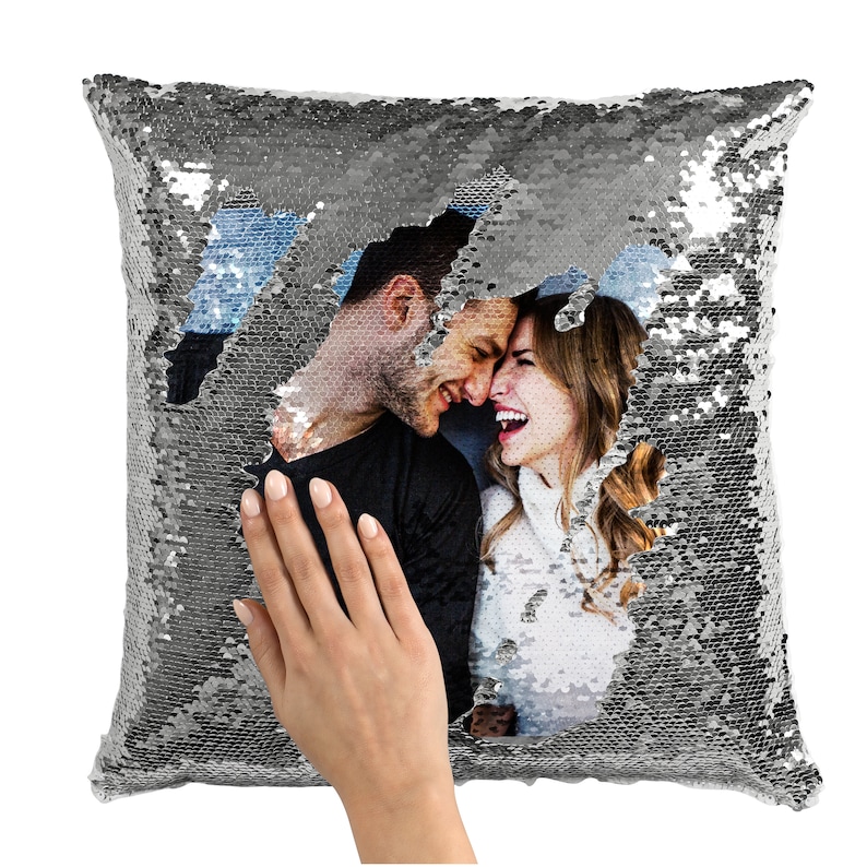 May include: A silver sequin pillow with a hidden photo of a couple smiling at each other. The photo is revealed by flipping the sequins.