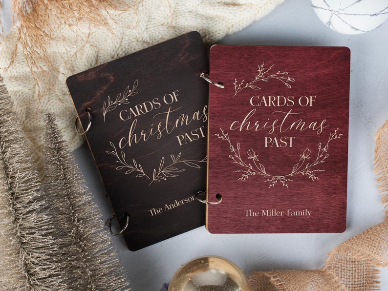 May include: Two wooden photo albums with a burgundy and black finish. The albums are decorated with a floral design and the text "Cards of Christmas Past". The albums are personalised with the names "The Anderson" and "The Miller Family".