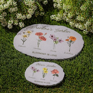 May include: Two gray stone garden markers with floral illustrations and the text "Grandma's Garden" and "Nana's Garden". The larger marker has names Deborah, Vanessa, James, and Nicholas. The smaller marker has names Madison, Jacob, and Daniella.