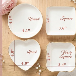 May include: Four white ceramic trinket dishes with gold rims in round, square, heart, and wavy square shapes. Text labels indicate dimensions: round is 4.1 inches, square is 3.6 inches, heart is 4.0 inches, and wavy square is 3.4 inches.