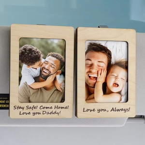 May include: Two wooden photo frames with family photos and text. One frame reads "Stay Safe! Come Home! Love you Daddy!" and the other says "Love you, Always!" The frames are attached to a car visor.