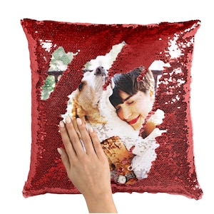 May include: Red sequin pillow with a photo of a person holding a dog. The photo is visible through a hole in the sequins.