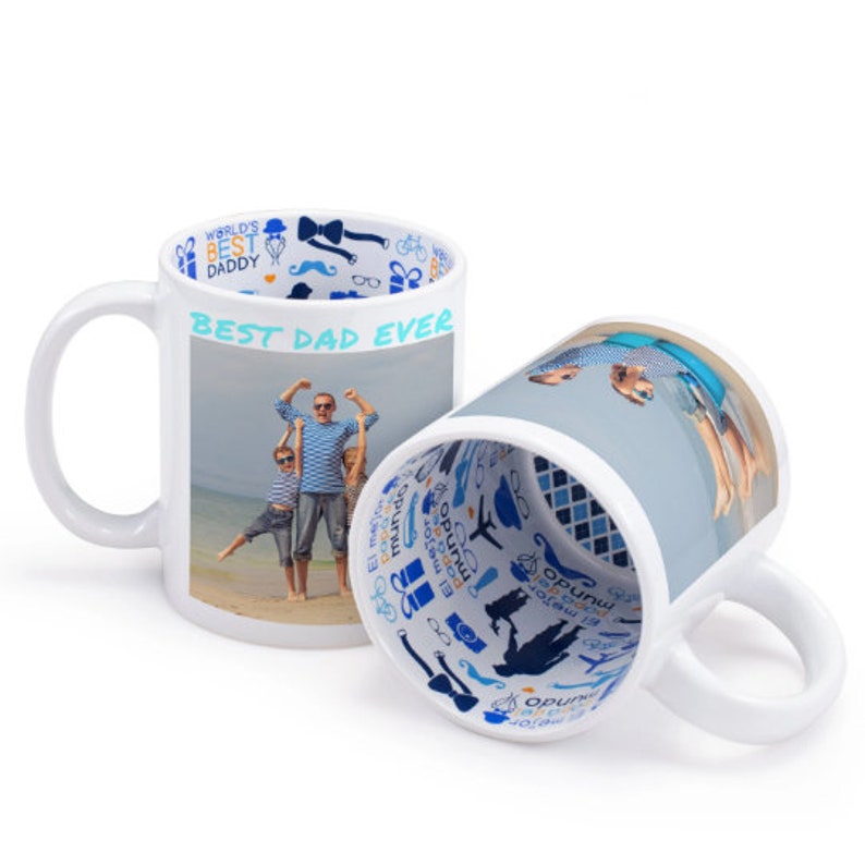 Puede incluir: Taza de cer&aacute;mica blanca con una foto de una familia en la playa. La taza tiene un borde azul con un patr&oacute;n de iconos azules y blancos y el texto "WORLD'S BEST DADDY" y "BEST DAD EVER".