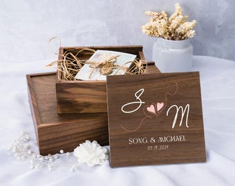 May include: A wooden box with a lid that has the initials "S & M" and the text "Song & Michael 05.19.2024" engraved on it. The box is filled with brown tissue paper and a white envelope.