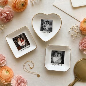 May include: Three white ceramic trinket dishes with gold-toned rims, each featuring a black and white photograph and printed text. One heart-shaped dish reads Summer 1996, one square dish reads I love you, Mommy, and one square dish reads Love you, Mom.