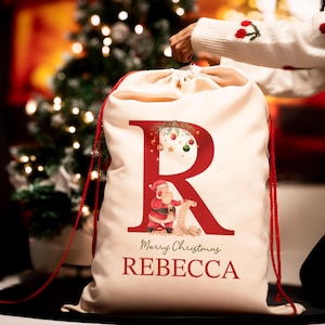 May include: A white Christmas stocking with a red letter R, a Santa Claus illustration, and the text "Merry Christmas REBECCA".